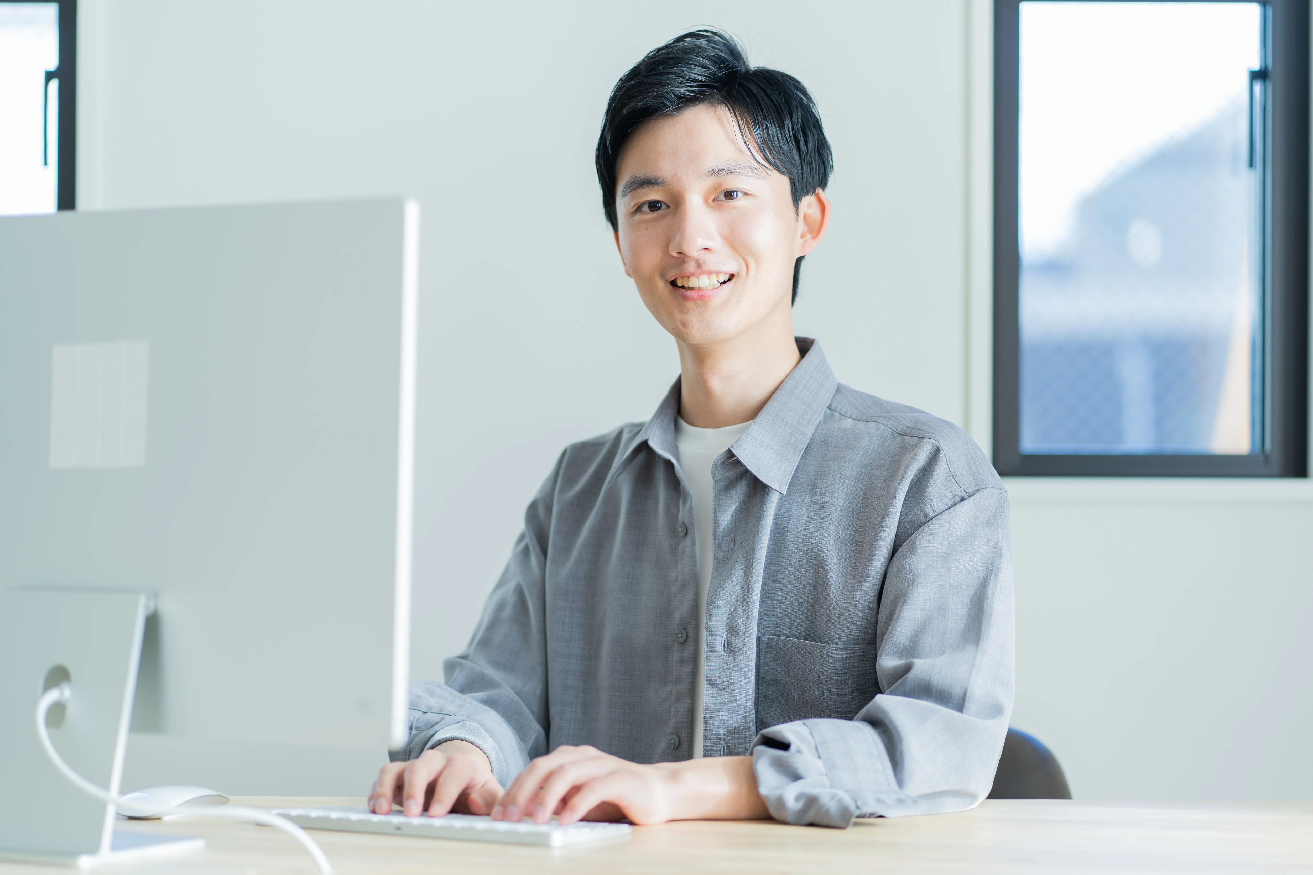 ノートパソコンを使いながら笑顔で座っている女性の写真